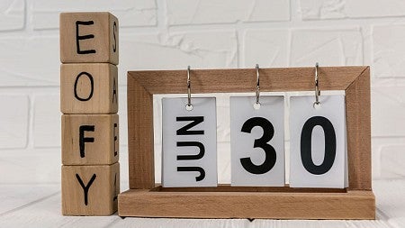 Wood blocks letters E O F Y and flip calendar with the date showing June 30.