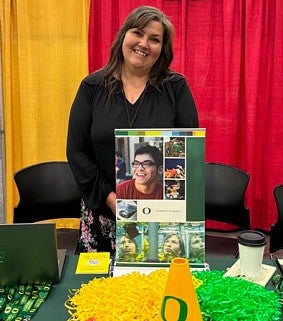 Isla Dane of PCS smiling at the UO hosted booth for OAME 2025 tradeshow.